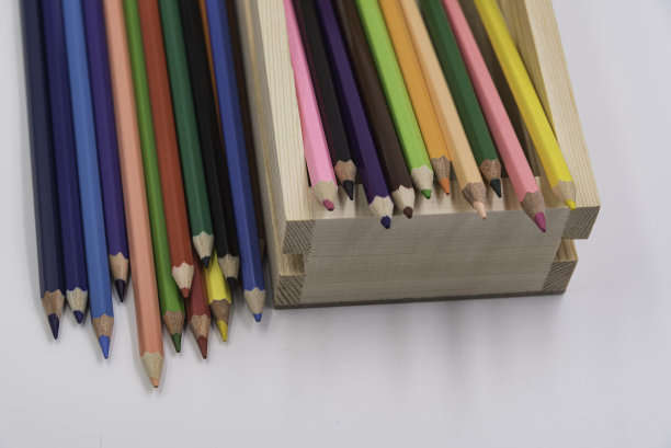 彩色木铅笔放在木箱里，铺在白色的背景上。图片下载
