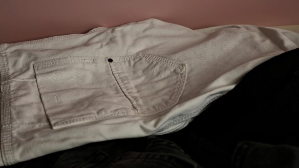 不同颜色的牛仔裤散落在粉红色的背景上图片下载