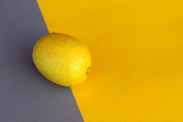 柠檬位于灰色和黄色的背景上，同时还有文字空间。图片下载