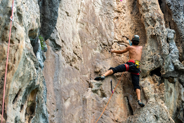 亚洲年轻人在热带岛屿的岩石山上爬山度假图片下载