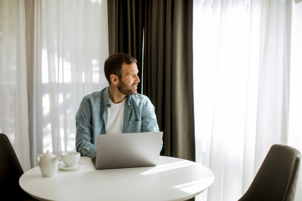 年轻人在客厅里用笔记本电脑喝茶图片下载