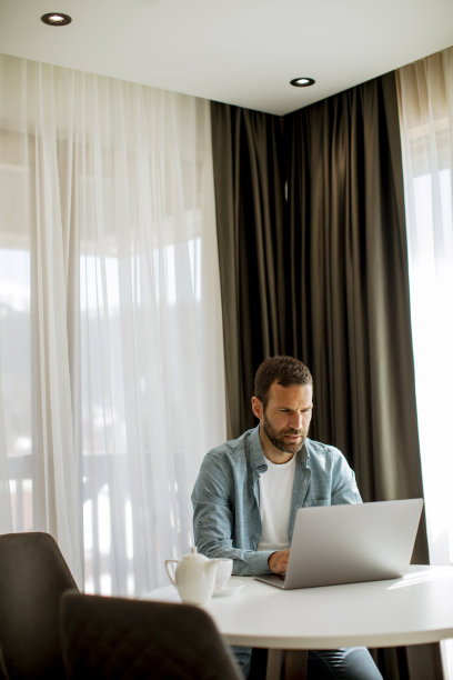 年轻人在客厅里用笔记本电脑喝茶图片下载