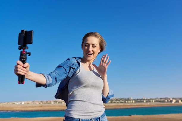 在海边用智能手机录制视频的中年妇女图片下载