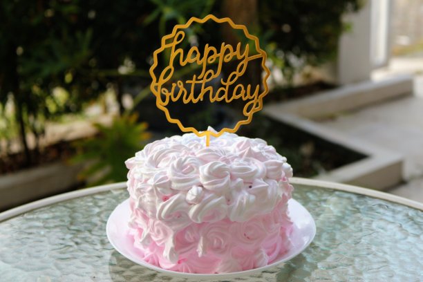 生日蛋糕与粉红色奶油花图案和生日快乐装饰。图片下载