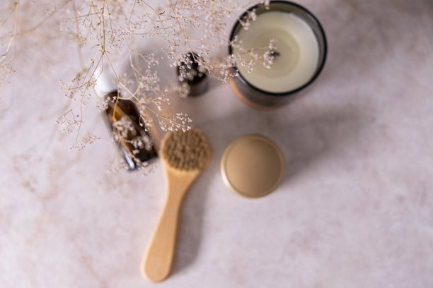 皮肤护理产品的油，脸按摩和鲜花在白色的桌子。生态友好的有机可重复使用的自我护理配件。图片下载