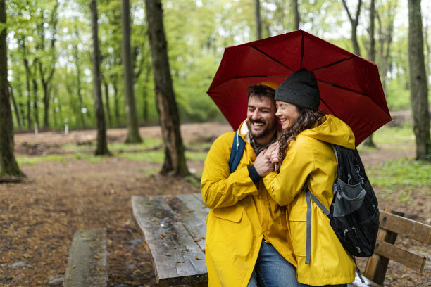 幸福可爱的情侣穿着雨衣在森林里享受雨天图片下载