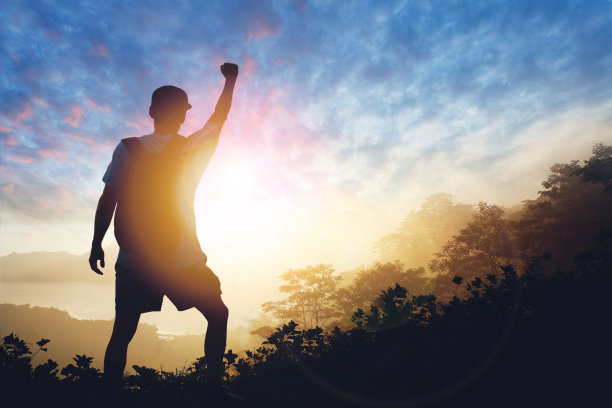 男人庆祝成功幸福的剪影在日落黄昏的天空背景图片下载