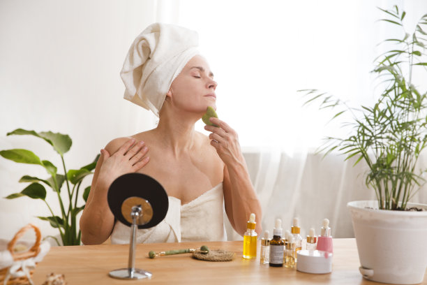 微笑女人35年多在毛巾上用刮沙石做面部按摩。化妆品的自然趋势。晨间卫生及护肤护理图片下载