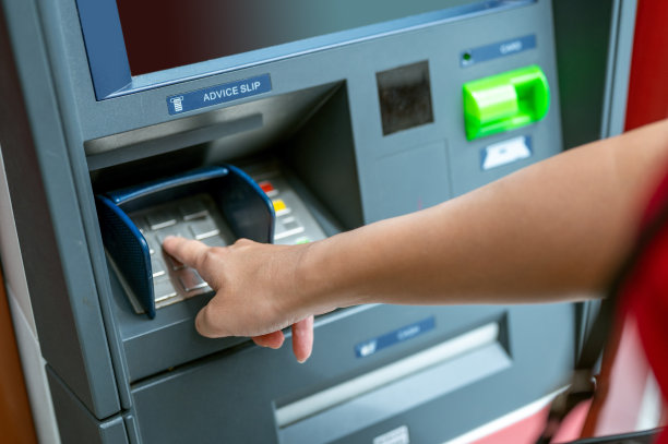 一名不明身份的女子从ATM机取款并输入密码图片下载