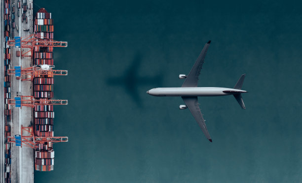 在货轮上方飞行的飞机。图片下载