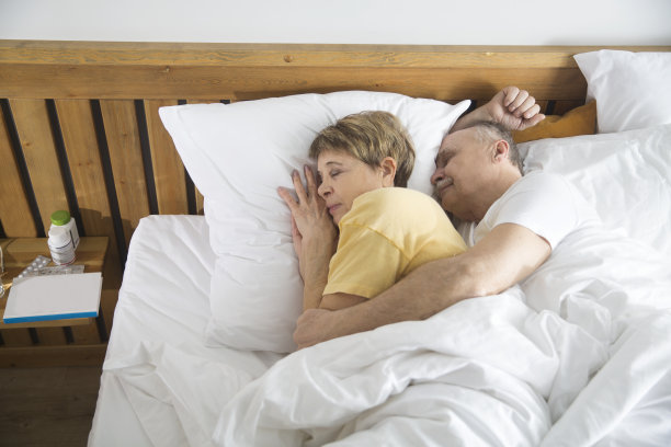 健康的老年人的生活方式。一对慈爱的老夫妇在家里的床上拥抱着睡觉图片下载