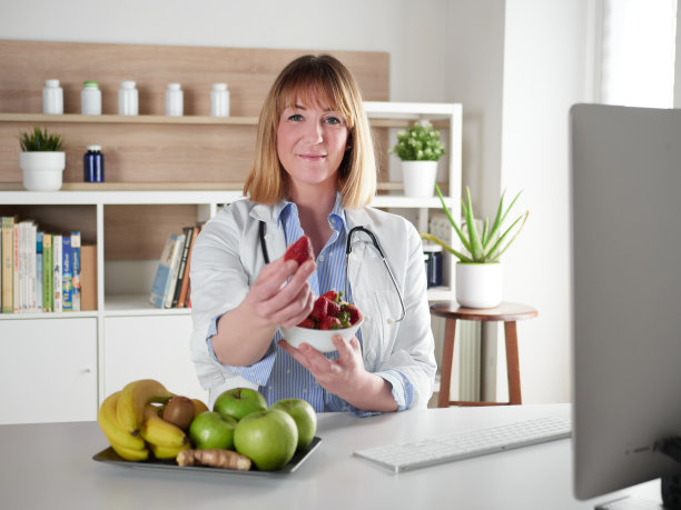 女营养师拿着一个草莓水果在办公室工作室图片下载