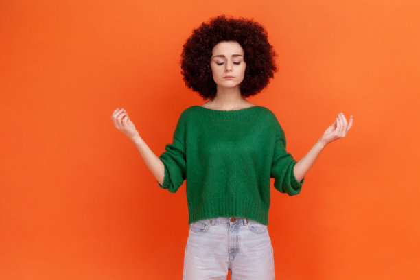 年轻成年女性肖像与非洲发型穿着绿色休闲风格毛衣感觉平静放松与和平的心态，瑜伽练习。图片下载