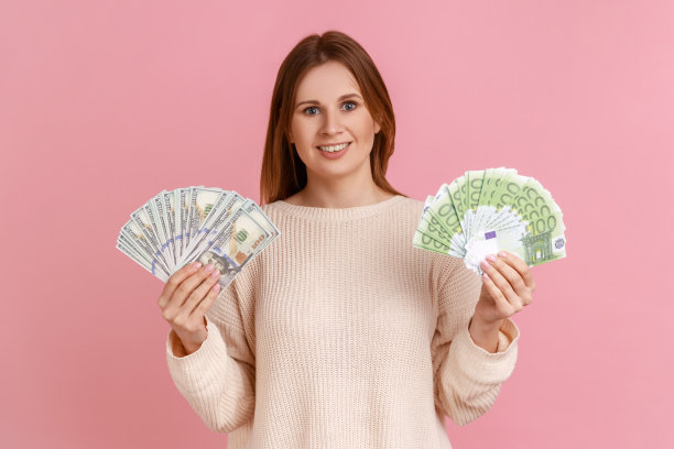 满意的金发富婆拿着两张欧元和美元的大扇子。看相机。图片下载