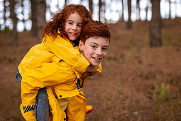 快乐的红头发兄弟姐妹在秋天的森林里玩图片下载