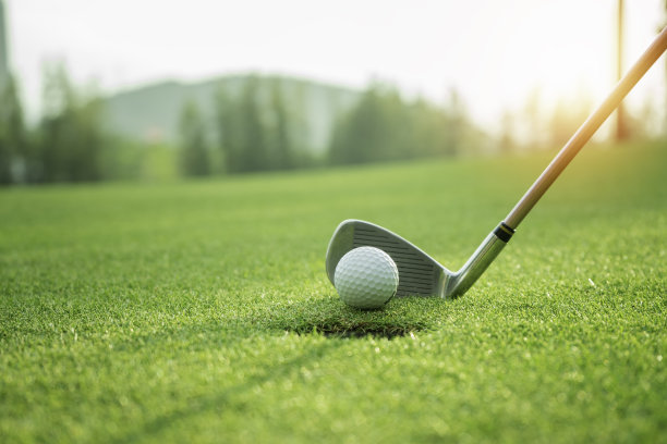 高尔夫球杆与高尔夫球放置在绿色在日落图片下载
