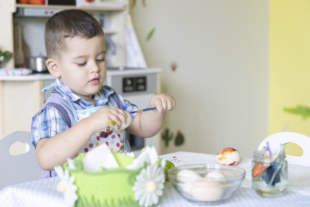 一个可爱的小男孩为复活节画彩蛋。复活节快乐。图片下载