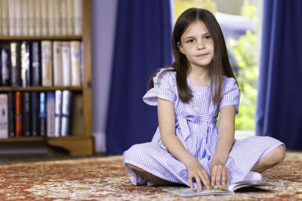 可爱的小女孩坐在地板上看书图片下载