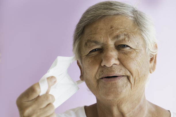 老妇人脱下她的外科口罩图片下载