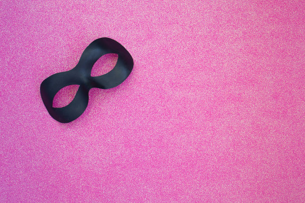 浅粉色背景上的黑色嘉年华面具图片下载