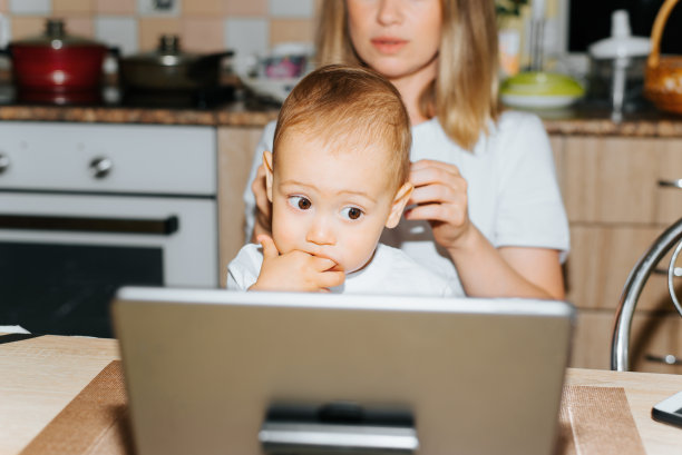 母亲,养育,照顾孩子。妈妈和孩子使用平板电脑，观看儿童教育视频。小男孩吮吸手指，在室内与母亲坐在一起看展示的小玩意图片下载