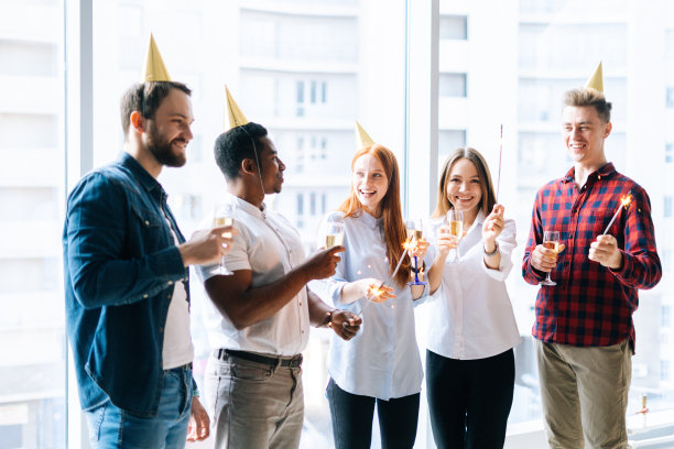 快乐的商业团队，年轻的多种族同事拿着孟加拉灯和碰杯香槟在公司派对图片下载