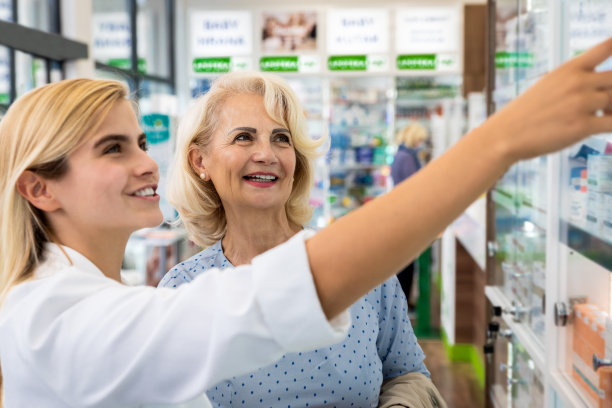 药剂师在药店向年长的女性顾客销售药物。图片下载