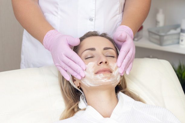 美容。可爱的年轻女子在美容院闭上眼睛接受面部清洁程序的特写照片。图片下载