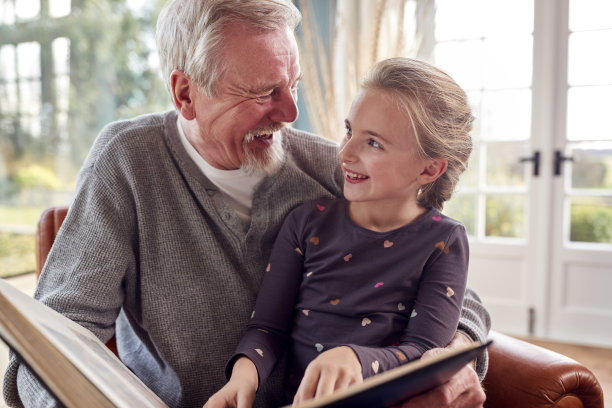 爷爷和孙女在家里的休息室一起看相册图片下载
