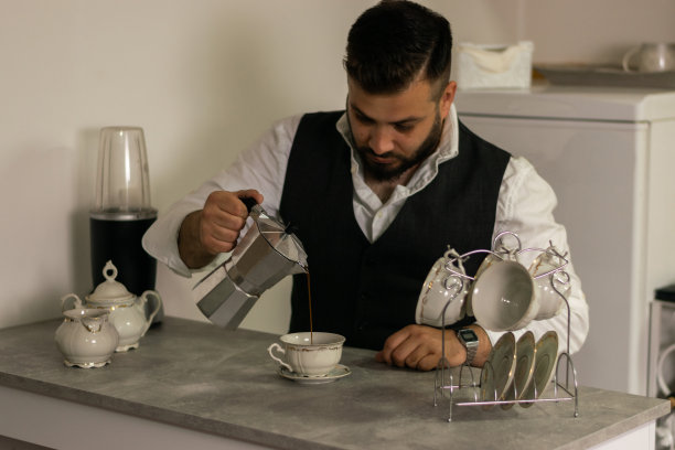 在家里工作的商人，喜欢喝一杯咖啡，在厨房倒咖啡，在笔记本电脑上工作时喝咖啡。图片下载