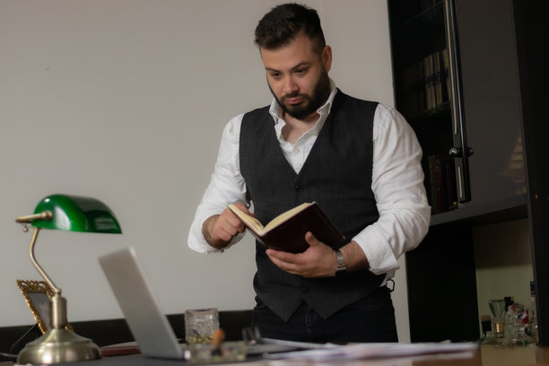 商人在看他的笔记本看他的笔记试图找到他需要的解决方案，在办公室工作到深夜图片下载