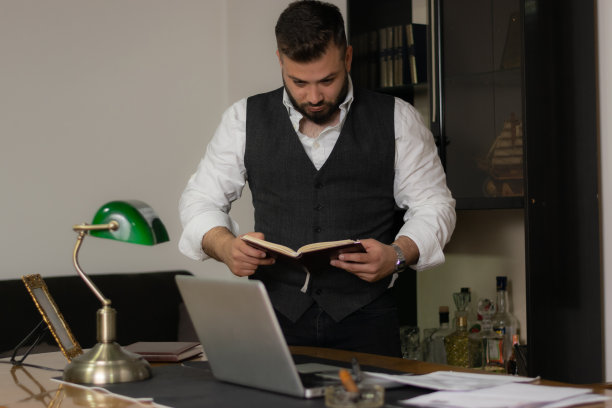 商人在看他的笔记本看他的笔记试图找到他需要的解决方案，在办公室工作到深夜图片下载