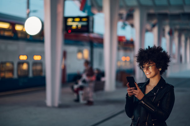 在火车站站台上用智能手机等车的女人图片下载