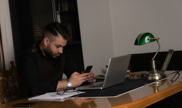 商人在办公室工作，用智能手机，打电话，发短信，坐在办公桌前。图片下载