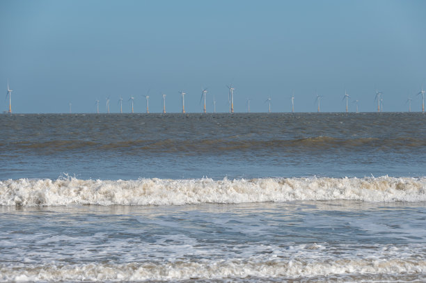 海滩、海浪和遥远的风力涡轮机图片下载