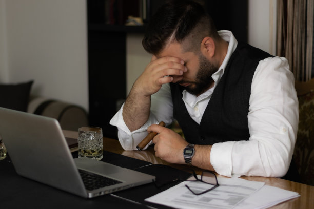 商人在他的办公室工作在他的办公桌上的笔记本电脑，在漫长的一天的办公室后，结束他的工作，抽着雪茄。图片下载