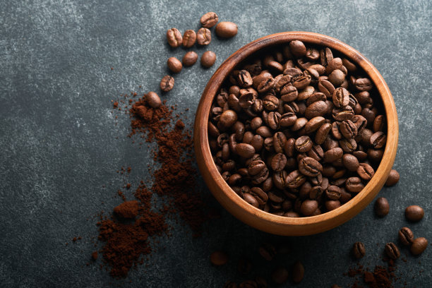 咖啡豆的背景。烤咖啡豆在木制竹碗，黑色的石头背景。前视图。咖啡的概念。模拟。图片下载