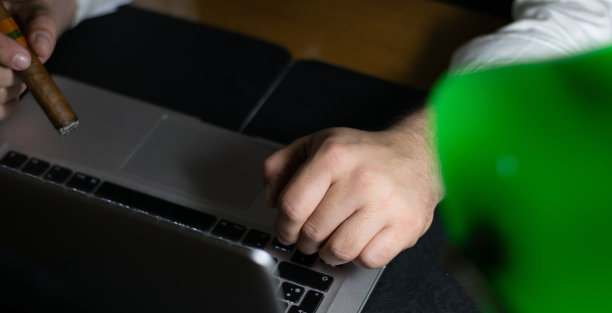 严肃英俊的商人，西装革履，倚在桌子上看图表。深夜工作的概念。工作到深夜为第二天做准备，完成他的工作。图片下载