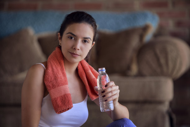 一名西班牙年轻女子在接受训练后，看着镜头，用瓶子喝水图片下载