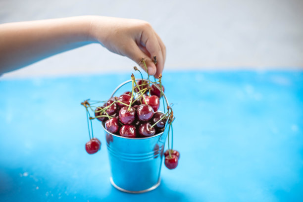 水果餐的概念与孩子手里拿着红色的有机樱桃。天然健康饮食和新鲜食品的理念。素食、营养、最小的风格。夏日乐趣和健康饮食的概念图片下载