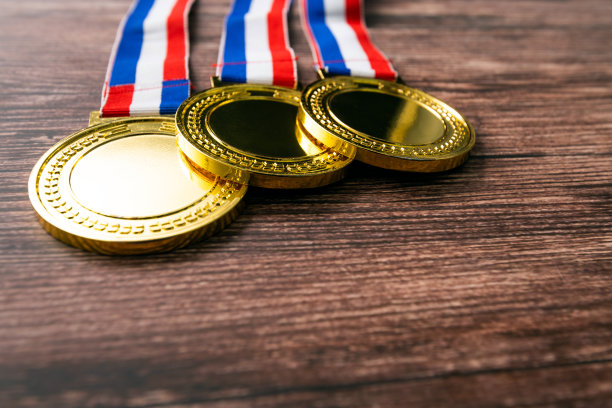 三枚金牌放在木桌上图片下载