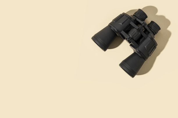 米色背景上的黑色双筒望远镜。俯视图，平面布局。图片下载