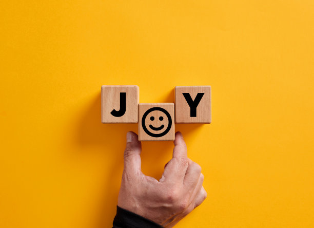 手把“快乐”这个词放在木块上，上面有一个笑脸符号。喜悦，幸福，愉悦，愉悦的情绪。图片下载