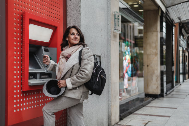 成熟的拉丁妇女手里拿着信用卡从自动柜员机取钱图片下载