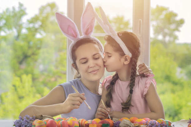 妈妈和女儿一起玩，为快乐的复活节画彩蛋。幸福的家庭为复活节做准备。可爱的兔子耳朵戴在头上图片下载