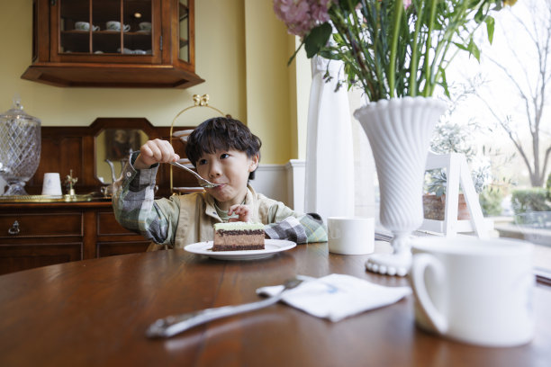 一个小男孩在厨房里吃蛋糕图片下载