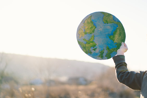 小男孩手里拿着星球，背景是绿色的春天图片下载