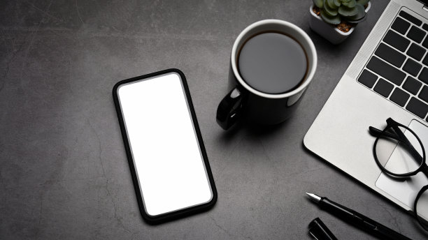 俯瞰现代工作场所与手机，笔记本电脑和咖啡杯在黑色的石头背景。图片下载