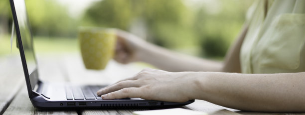 年轻女性在公园里使用笔记本电脑的横横幅-千禧一代女性自由职业者在网站上更新远程户外工作的内容-技术和远程工作的概念图片下载