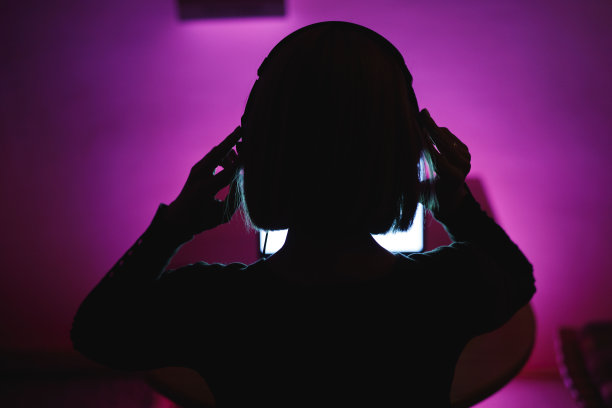 女人在开始用笔记本电脑玩视频游戏前戴上耳机图片下载